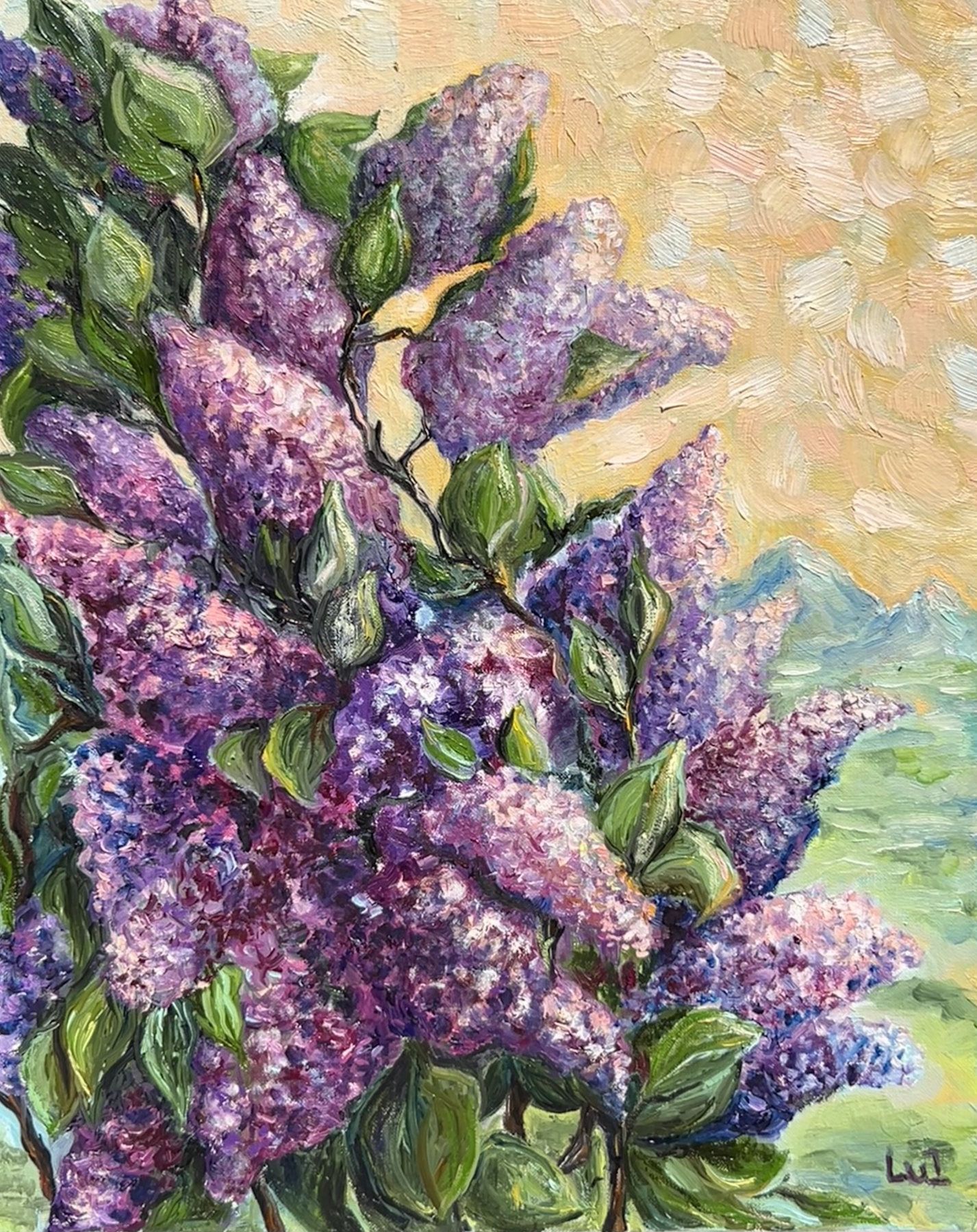 Purple and pink lilac blossoms with green leaves against a warm sky and distant mountains.