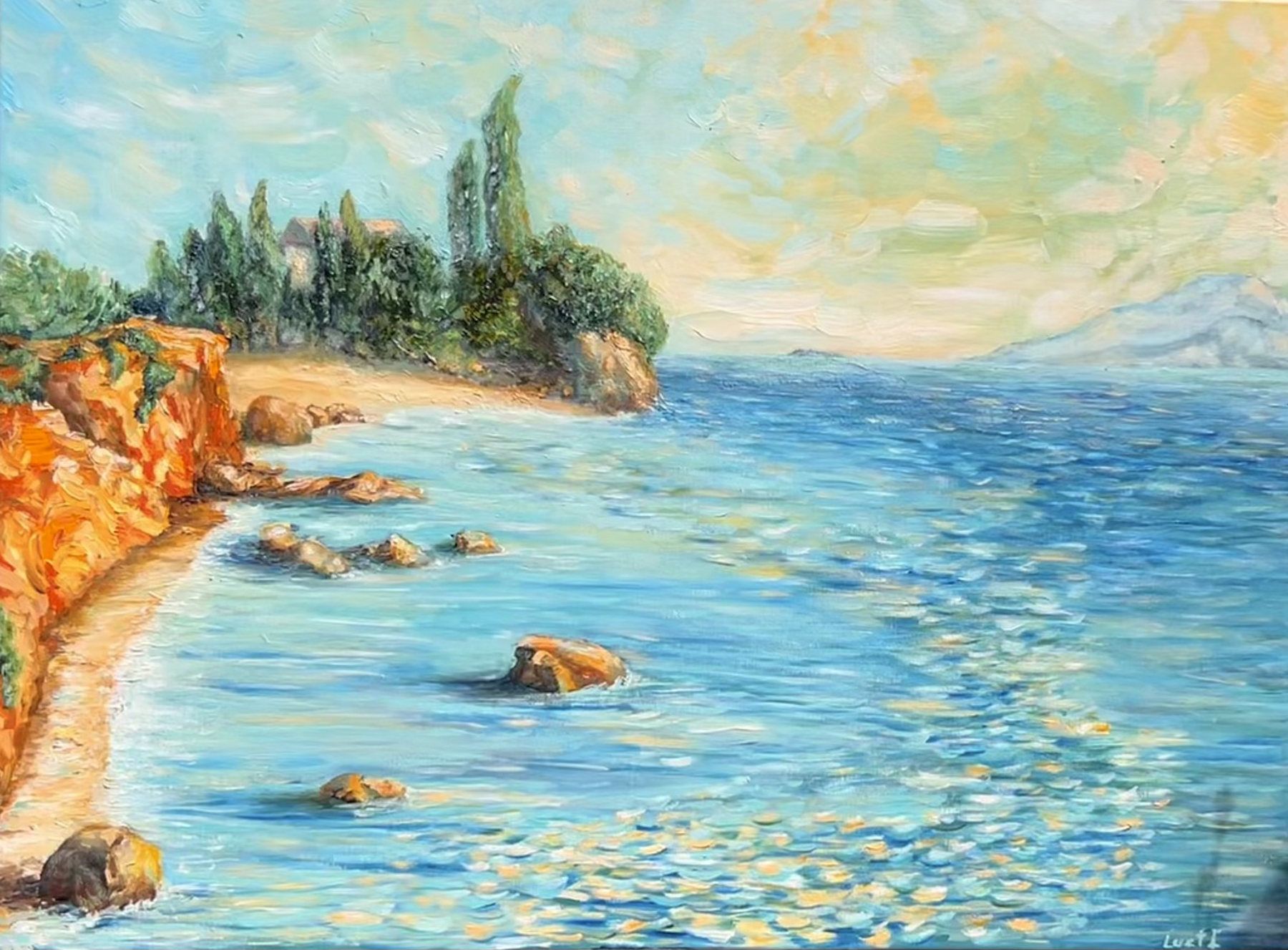 Turquoise coastal bay with ochre cliffs, a wooded headland and distant mountains.
